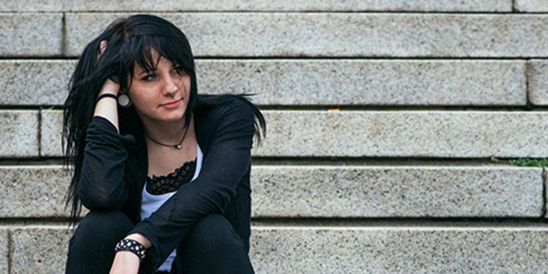 A teenager sitting on some steps